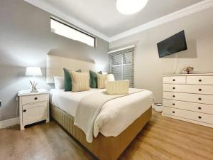 een slaapkamer met een bed, een ladekast en een televisie bij Coastal Hospitality - Beach Club 205 in Mosselbaai +31 foto's