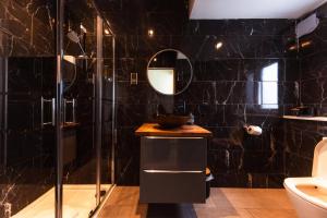 a black tiled bathroom with a sink and a shower at Luxury Seaview Cottage by Fairy Pools 3 in Carbost +17 photos