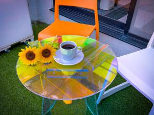 a glass table with a cup of coffee and sunflowers on it at MANDO Hotel 101 in Tokyo