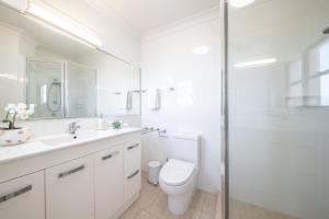 a white bathroom with a toilet and a shower at Blue Beyond Airlie in Airlie Beach