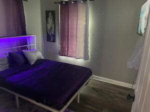 a bedroom with a bed with purple sheets and a window at Beehive Cottage in Woodward