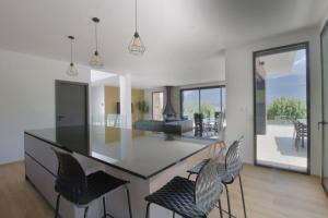 CatonにあるVilla d'exception Piscine vue et accès lac directのバーチェア付きの島とリビングルームのあるキッチン