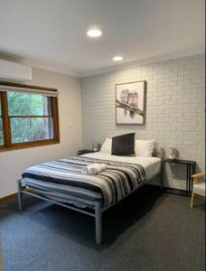 una cama en una habitación con una pared de ladrillo en Kangaroo House, en Halls Gap