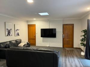 Una sala de estar con un sofá y un televisor de pantalla plana. en Kangaroo House, en Halls Gap