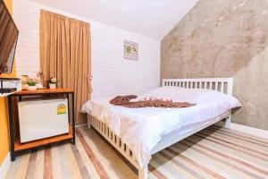ein Schlafzimmer mit einem Bett und einem Fernseher darin in der Unterkunft V Village Hotel Saraburi in Ban Muak Lek