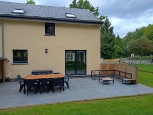 a patio with a table and chairs in front of a house at Maison des Fées d'Achouffe in Houffalize