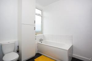 a white bathroom with a tub and a toilet at Modern 3 Bedroom Home with Parking in Southend in Southend-on-Sea