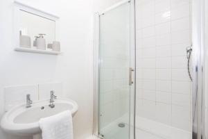 a white bathroom with a sink and a shower at Modern 3 Bedroom Home with Parking in Southend in Southend-on-Sea