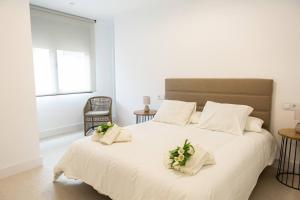 a bedroom with a large white bed with flowers on it at Royar 4 ático in Jaén +14 photos