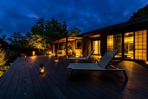 a wooden deck with two chairs on it at night at 箱根懐來 in Hakone +12 photos