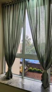 a window with green curtains in a room at CASA HILLSIDE Dapoli 2BHK AC Apartment in Dapoli