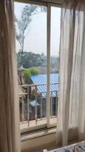 a window with white curtains in a room at CASA HILLSIDE Dapoli 2BHK AC Apartment in Dapoli