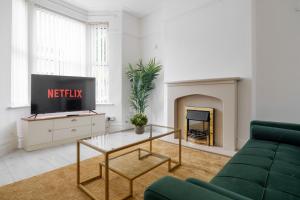 Una sala de estar con un sofá verde y un televisor. en Mersey View 4 Bedroom by Liverpoollux Next To Everton Stadium, en Liverpool