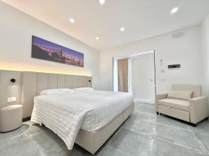 a white bedroom with a large bed and a chair at Hotel Ohana in Rome +13 photos