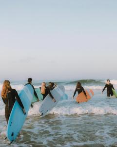 a group of people standing in the ocean with surfboards at Surf and Stay Villa Anza Taghazout Tamraght in Agadir