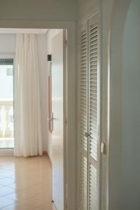 Una habitación con puertas blancas y un pasillo con suelo. en Apartamentos Dominique, en La Manga del Mar Menor