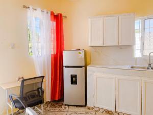 a kitchen with a refrigerator and a chair in it at Guest House A&H - Boca Chica Beach & Airport in Boca Chica