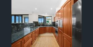 a kitchen with wooden cabinets and black counter tops at Executive Penthouse Apartment in Wollongong