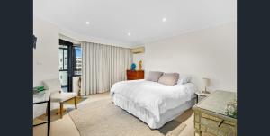 ウーロンゴンにあるExecutive Penthouse Apartmentの白いベッドルーム(ベッド1台、テーブル、椅子付)