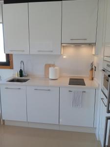 a white kitchen with white cabinets and a sink at RESIDENCIAL A MAMOA in Carreira
