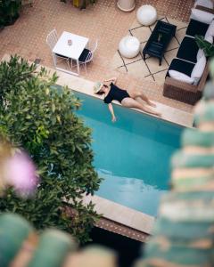 Eine Frau liegt in einem Schwimmbecken in der Unterkunft Riad Rafaele & SPA in Marrakesch