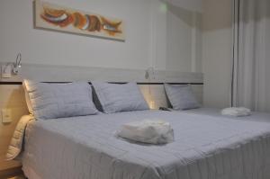 Una cama blanca con una toalla encima. en Hotel Raio de Sol, en Guarapari