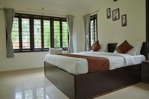 a bedroom with a large bed in a room with windows at melberry villa in Sānand