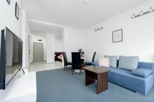 ein Wohnzimmer mit einem blauen Sofa und einem Tisch in der Unterkunft Spacious Villa Tarsis Studio in Kolobrzeg by Noclegi Renters in Luboszyce