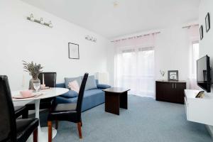 ein Wohnzimmer mit einem blauen Sofa und einem Tisch in der Unterkunft Spacious Villa Tarsis Studio in Kolobrzeg by Noclegi Renters in Luboszyce + 19 Fotos