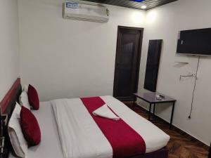 a bedroom with a bed with a red and white blanket at Hotel Rudra in Haldwāni