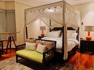 a bedroom with a canopy bed and a chair at Casa Acantilado Oslob - 3BR in Oslob