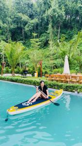 a man is sitting on a paddle boat in the water at Rolling Hill Resort in Xóm Trông