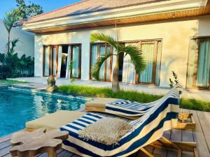 a swimming pool next to a house with a palm tree at MerSea Villa -Brand new Balangan beach -luxurious 4 bdr with huge pool in Perean
