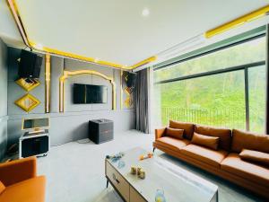 a living room with a couch and a large window at Rolling Hill Resort in Xóm Trông