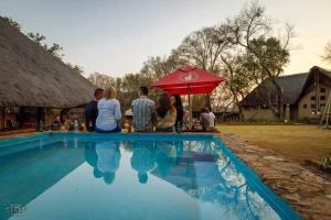 a group of people sitting next to a swimming pool at Harties Is Africa Safari Lodge in Hartbeespoort
