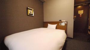 a bedroom with a large white bed in it at Hotel Route-Inn Tsuruga Ekimae in Tsuruga