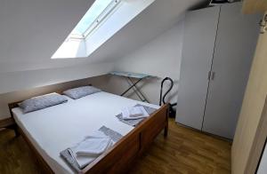 a bedroom with a bed with white sheets and a skylight at Apartments Sv. Jelena 2 in Pag