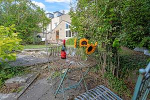 a table with a bottle of wine and sunflowers on it at Whitehall Cottage in Painswick