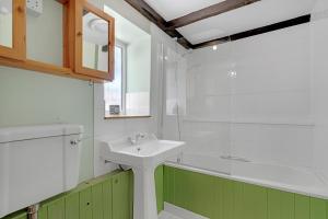 a bathroom with a white sink and a shower at Whitehall Cottage in Painswick