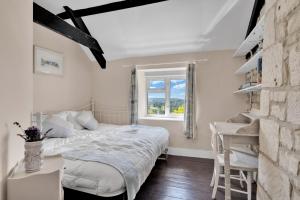a bedroom with a bed and a desk and a window at Whitehall Cottage in Painswick
