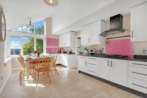 a kitchen with white cabinets and a table with chairs at Whitehall Cottage in Painswick +17 photos