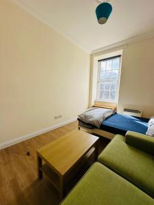 a room with a bed and a couch and a window at Cozy Room In Sauchiehall Street in Glasgow