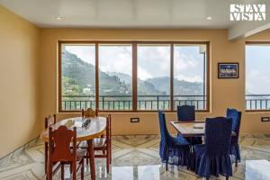 a dining room with a table and chairs and a large window at StayVista at Kurinji Amaze Kodai with WiFI & Heater in Kodaikānāl
