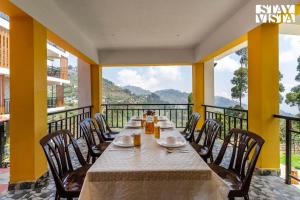 a dining room with a table and chairs on a balcony at StayVista at Kurinji Amaze Kodai with WiFI & Heater in Kodaikānāl