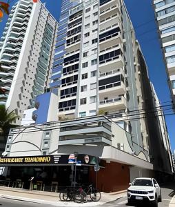 Dos edificios altos con bicicletas estacionadas frente a ellos. en 30m da PRAIA, Climatizado e Wi-Fi, en Balneário Camboriú