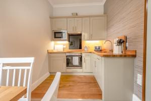 a kitchen with white cabinets and a wooden floor at Bethby Beck Apartment Keswick at The Lairbeck in Keswick