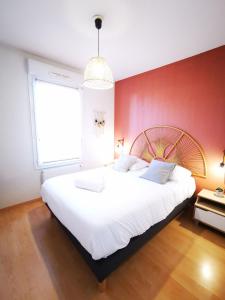 a bedroom with a large white bed with a red wall at Chez Manue et Ludo centre ville in Thonon-les-Bains