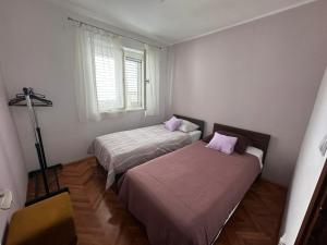 two beds in a small room with a window at Apartment Boni in Šibenik
