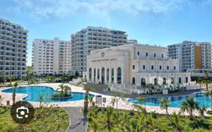 a large white building with two pools and palm trees at Family friendly modern flat in Caesar Resort &SPA, Long Beach İSKELE, KKTC in Iskele