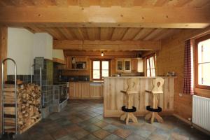 a kitchen with wooden cabinets and a counter with wooden stools at Almstallhütte in Pruggern